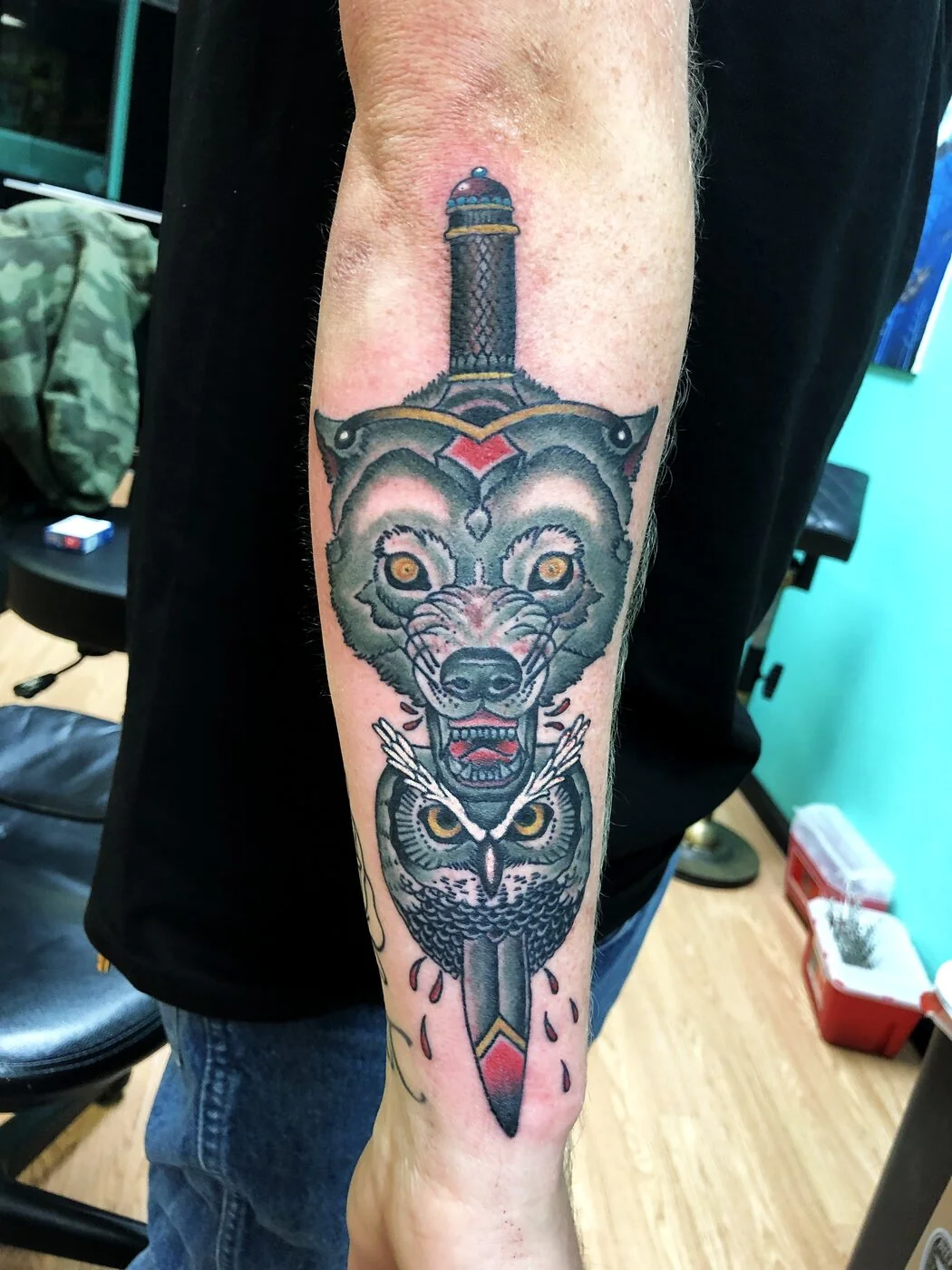 American Traditional wolf and owl sharing a dagger tattoo on forearm by 2bit (Chris Curren) at Lost at Sea Tattoo, Chinatown, Honolulu