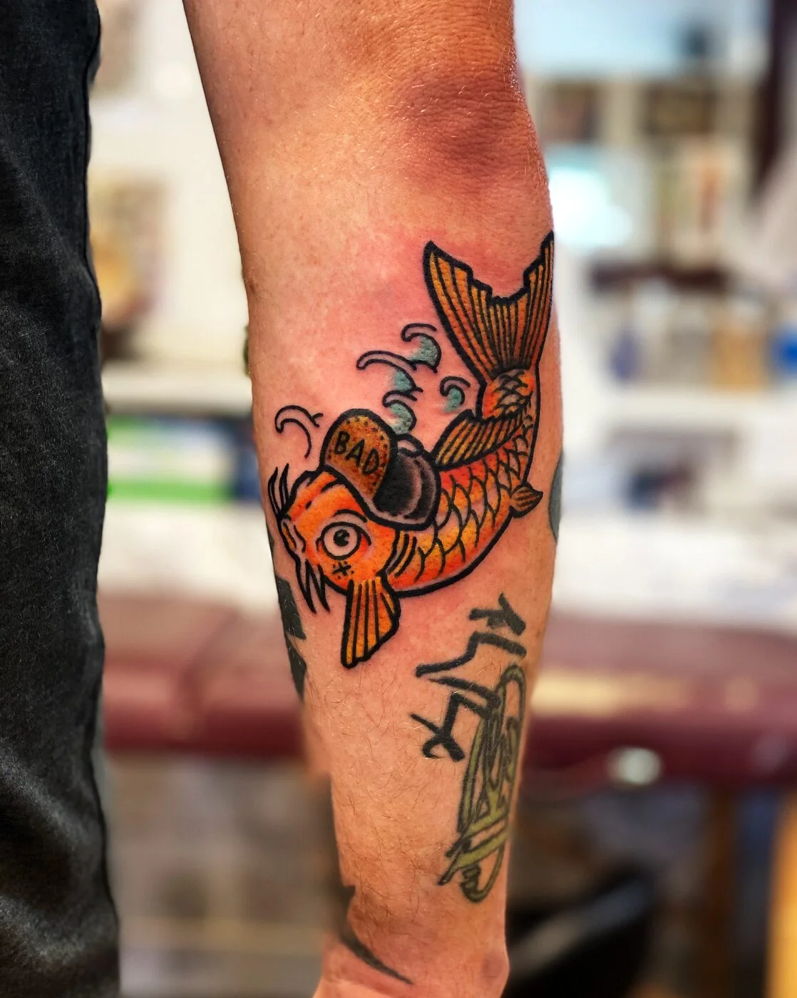 American Traditional koi fish with BAD baseball cap tattoo on calf by 2bit (Chris Curren) at Lost at Sea Tattoo, Chinatown, Honolulu
