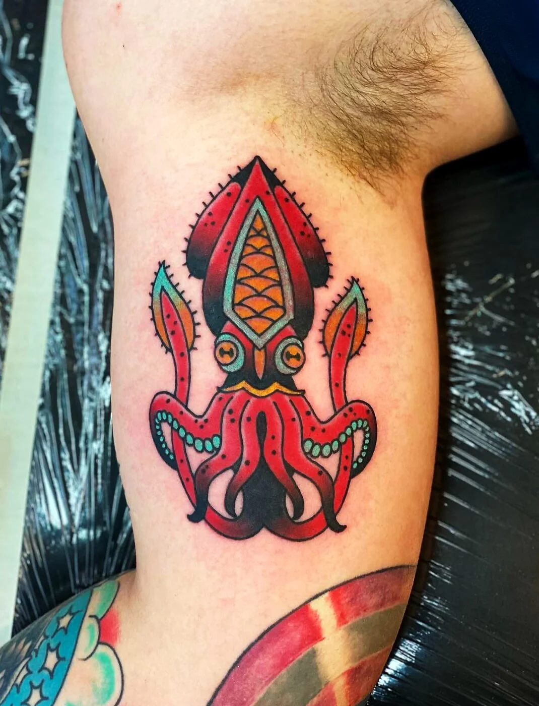 American Traditional red squid with green tentacle accents tattoo on bicep by 2bit (Chris Curren) at Lost at Sea Tattoo, Chinatown, Honolulu
