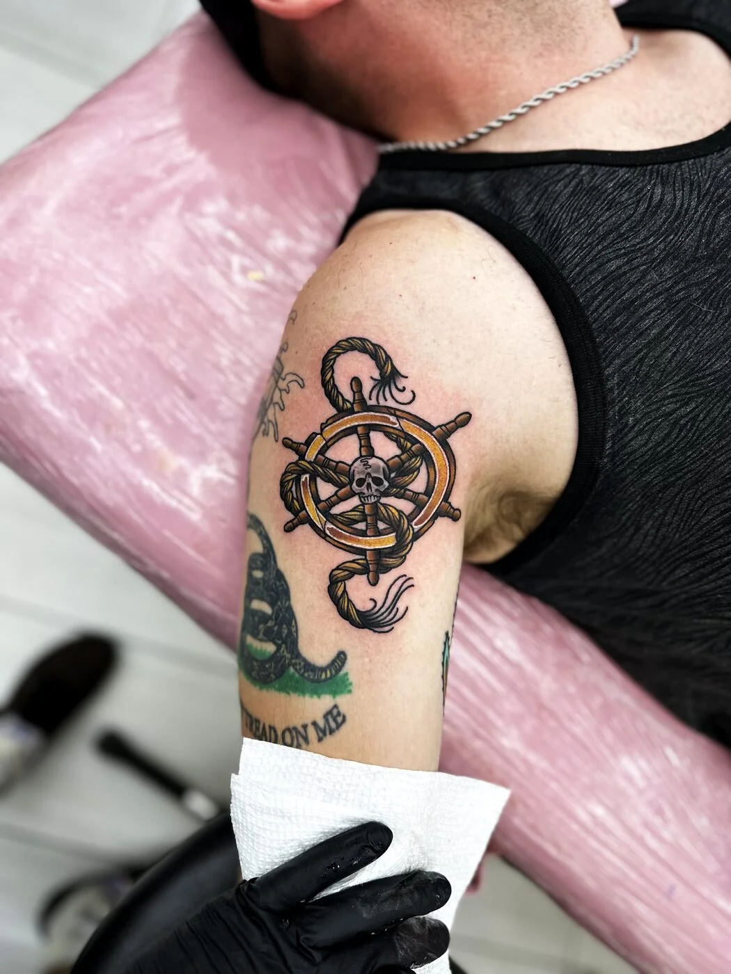 American Traditional ship's wheel with skull, rope and snake tattoo on shoulder by 2bit (Chris Curren) at Lost at Sea Tattoo, Chinatown, Honolulu