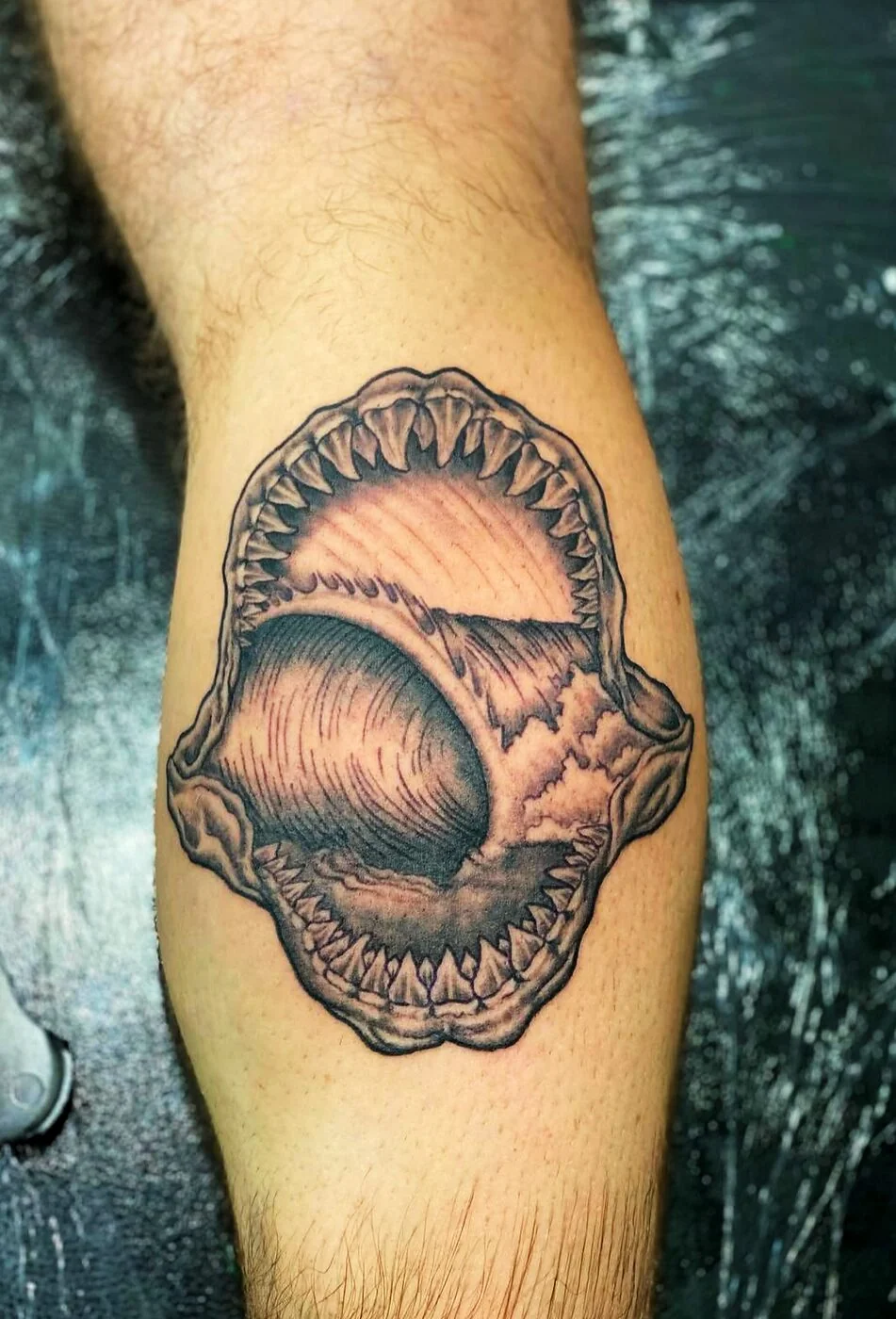 Black & Grey shark jaws with wave inside tattoo on calf by 2bit (Chris Curren) at Lost at Sea Tattoo, Chinatown, Honolulu