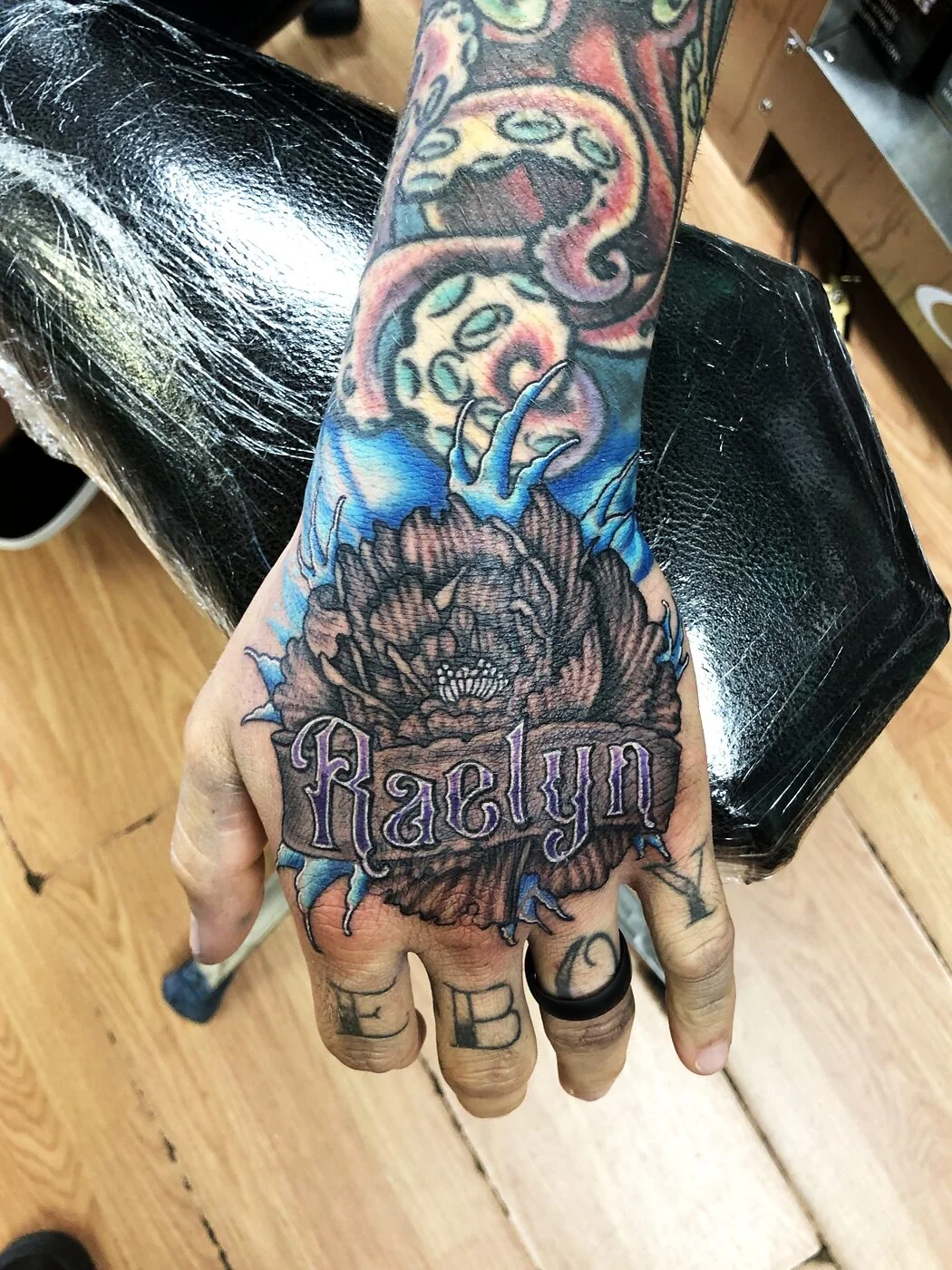 Color Realism octopus tentacles and peony with name banner tattoo on hand by 2bit (Chris Curren) at Lost at Sea Tattoo, Chinatown, Honolulu