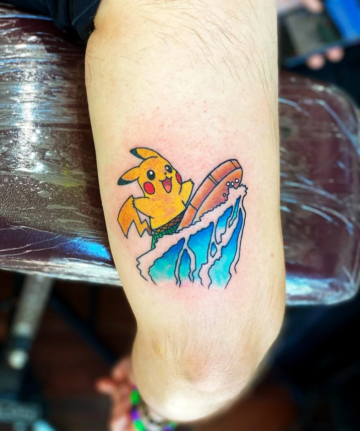 Illustrative Pikachu surfing a wave tattoo on calf by 2bit (Chris Curren) at Lost at Sea Tattoo, Chinatown, Honolulu